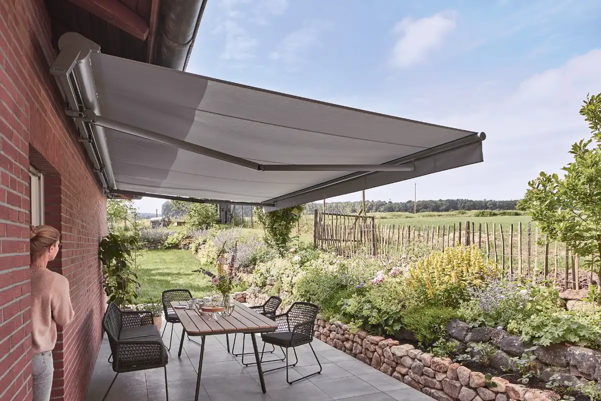 Terrasse mit Markise und Gartenblick Frau steht unter einer ausgefahrenen Markise auf einer Terrasse mit Gartenblick