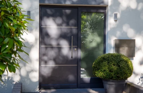 Alu- oder Kunststoffhaustür in grau neben einer großen Fensterscheide