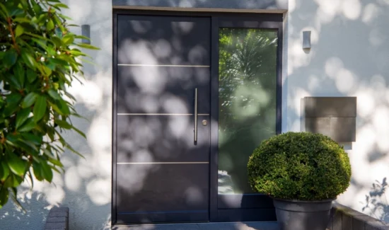 Alu- oder Kunststoffhaustür in grau neben einer großen Fensterscheide