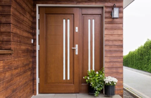 Haustür aus dunkelbraunem Holz an holzverkleideter Fassade