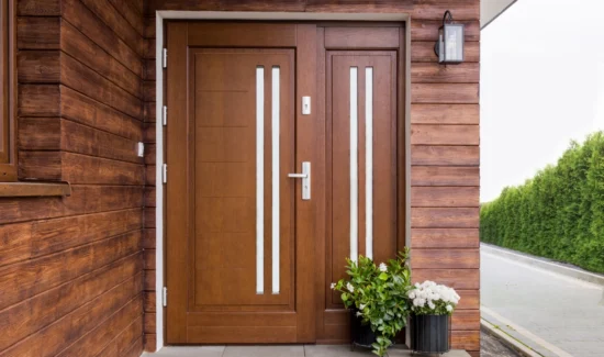 Haustür aus dunkelbraunem Holz an holzverkleideter Fassade